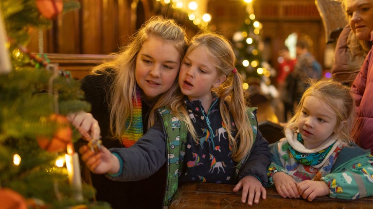 A family looking at the decorated community Christmas trees at Killerton